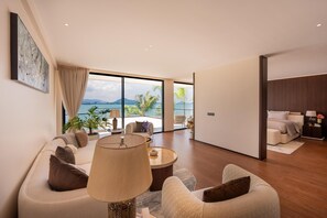 A modern living room with a large window, a sofa set, a coffee table, and a view of the sea. - Sea Cloud Residence (Tambon Wichit)