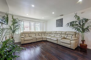 Ein Ecksofa in einem Wohnzimmer mit Holzboden und Topfpflanzen.