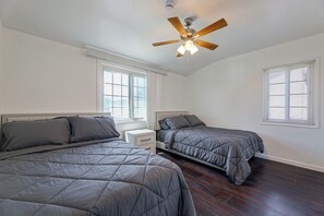 Ein Schlafzimmer mit zwei Betten, einem Deckenventilator und einem Fenster mit Jalousien.