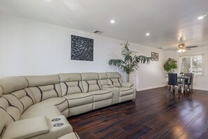 A modern living room with a sectional sofa, a dining table with chairs, and a ceiling fan. - Prime Los Angeles Spot! 1 Mi to SoFi, Intuit Dome (Los Angeles)