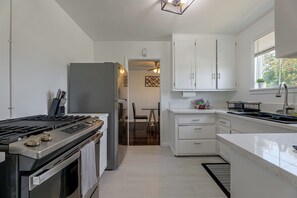 A modern kitchen with white cabinetry, a stainless steel range, and a built-in oven.