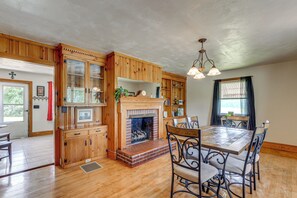 A spacious dining area with a brick fireplace, wooden cabinetry, and a dining table with chairs. - Quiet Stuart Retreat w/ Yard & Fireplace (Stuart)
