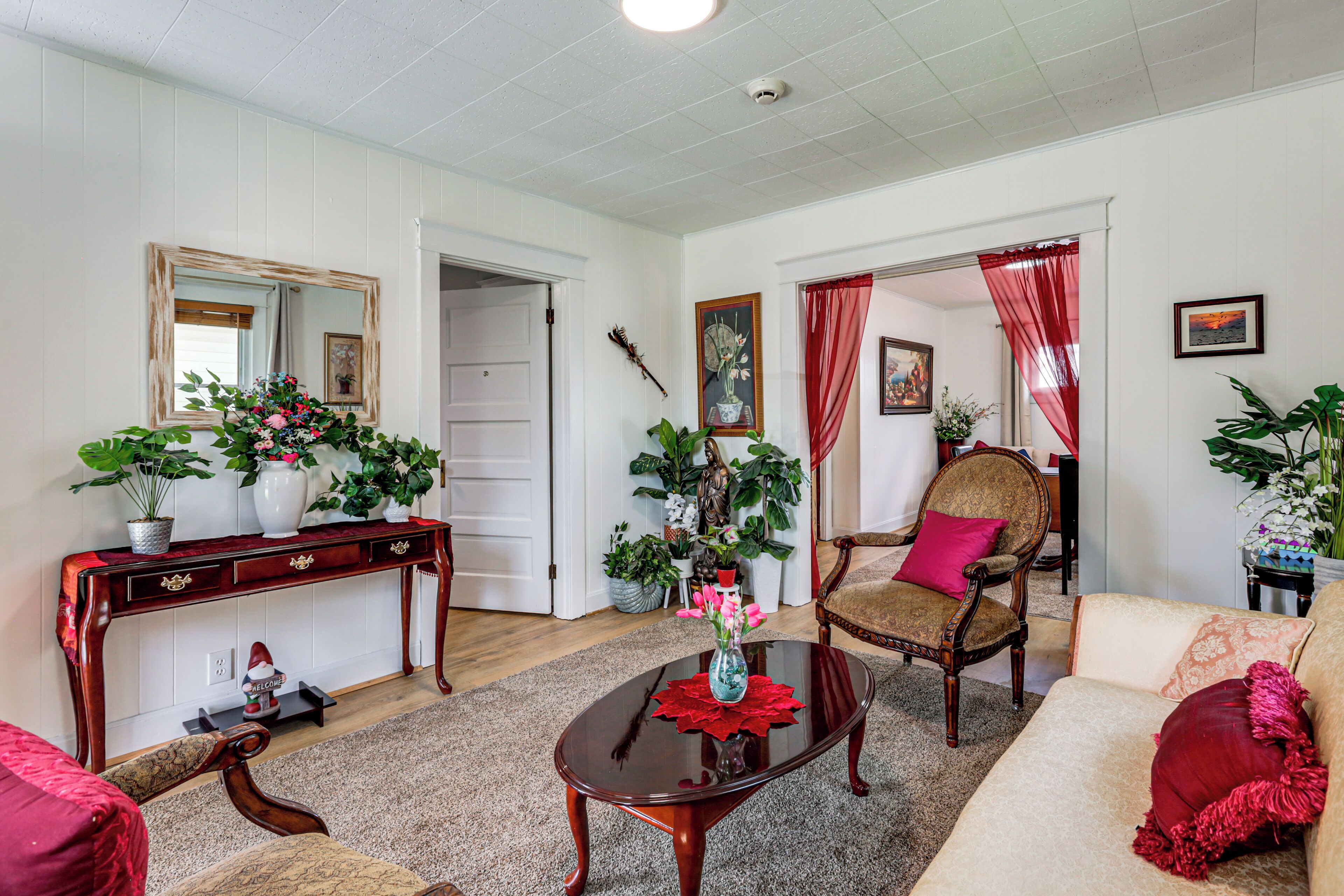Sala de estar com sofá, poltrona, mesa de centro e aparador com espelho e objetos decorativos.
