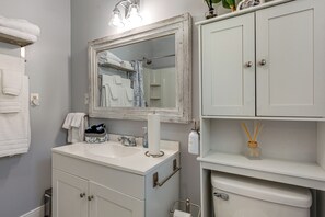 Un bagno con un lavandino bianco, uno specchio con cornice anticata, un porta asciugamani e un mobile con specchio.