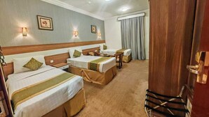 A hotel room with two beds, a wooden headboard, a desk, and a chair. - sama hijaz almaqam Hotel (Mecca)