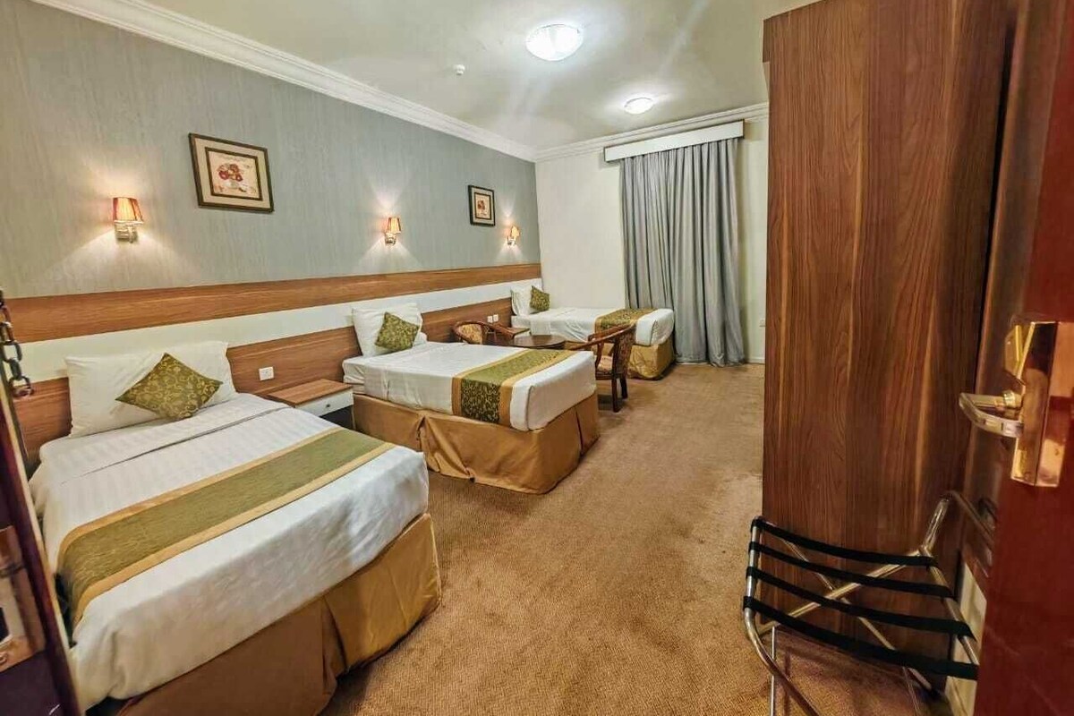 A hotel room with two beds, a wooden headboard, a desk, and a chair.