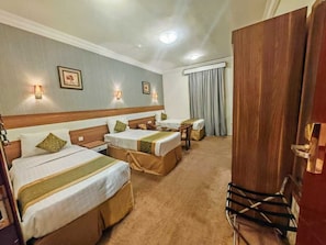 A hotel room with two beds, a wooden headboard, a desk, and a chair. - sama hijaz almaqam Hotel (Mecca)