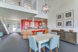 Una cocina moderna con una isla central, detalles en rojo y un comedor con mesa y sillas.