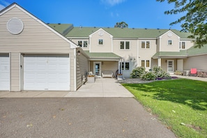 A residential building with a garage, a covered porch, and a well-maintained lawn. - Mille Lacs Lakefront Townhome: Walk to Marina! (Onamia)