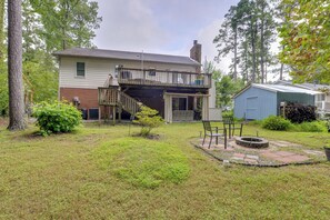 A two-story house with a front porch, a small backyard with a fire pit, and a shed. - Easy Raleigh Access! Quaint Apt w/ Patio (Garner)