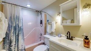 A bathroom with a bathtub, toilet, sink, and a shower curtain with a forest pattern. - Easy Raleigh Access! Quaint Apt w/ Patio (Garner)