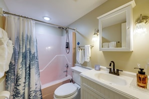 A bathroom with a bathtub, toilet, sink, and a shower curtain with a forest pattern. - Easy Raleigh Access! Quaint Apt w/ Patio (Garner)