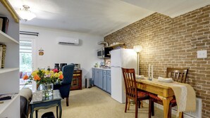 A compact kitchen with a dining area, a brick wall, and a window. - Easy Raleigh Access! Quaint Apt w/ Patio (Garner)