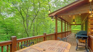Eine Holzterrasse mit Tisch und Stühlen, umgeben von üppiger Vegetation.