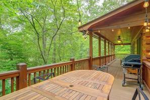 A wooden deck with a table and chairs, surrounded by lush greenery. - Private Hot Tub & Deck! Cherry Log Gem (Cherry Log)