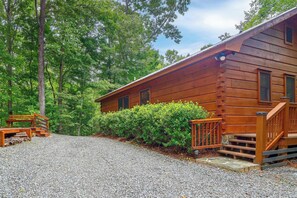 A wooden cabin with a gravel driveway, surrounded by trees and a well-maintained hedge. - Private Hot Tub & Deck! Cherry Log Gem (Cherry Log)