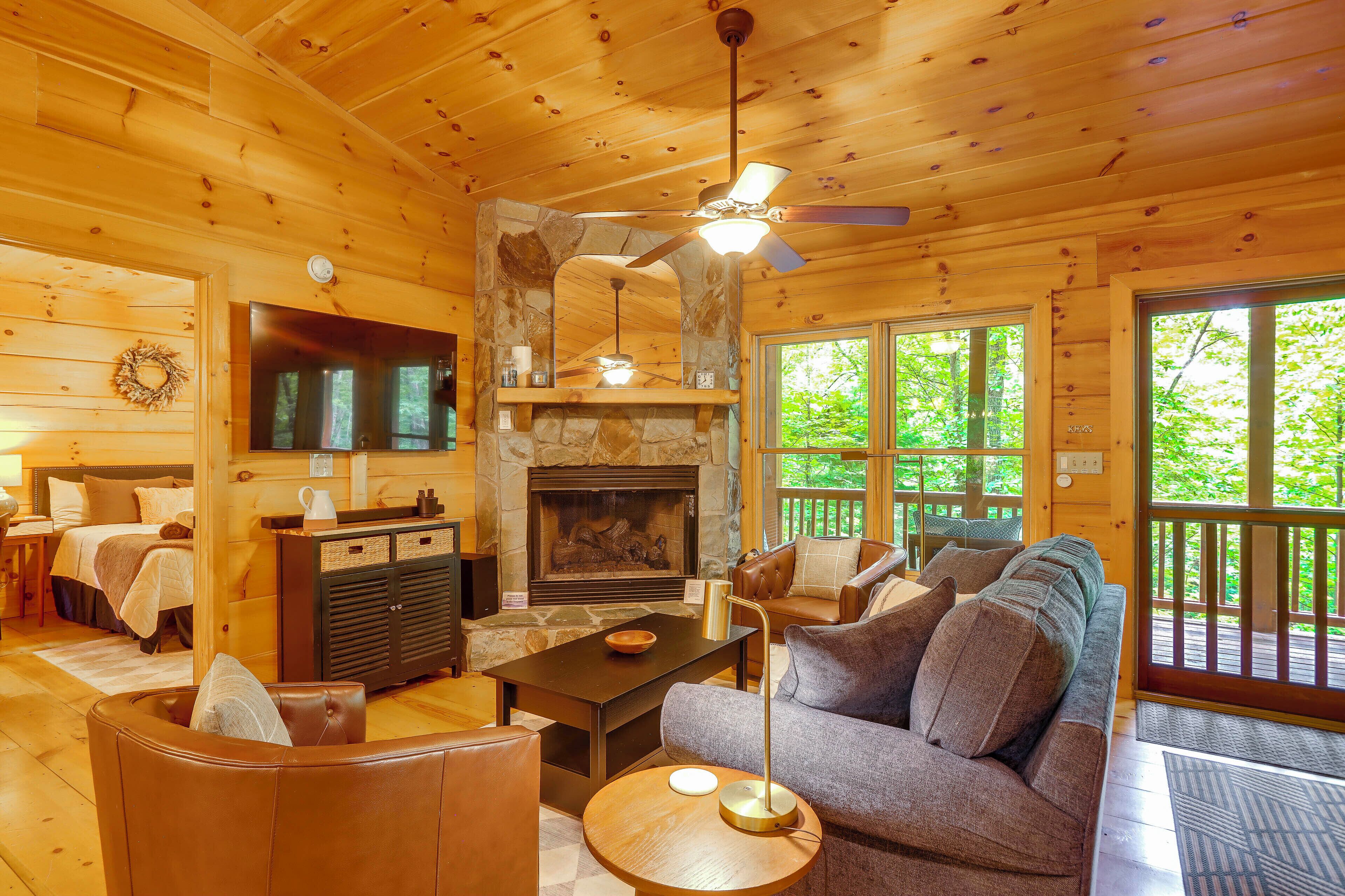 L’intérieur chaleureux d’un chalet avec une cheminée, des murs en bois, un canapé et un coin repas.