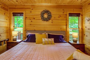 Ein Schlafzimmer einer Holzhütte mit Bett, Kissen, Nachttischen und einem Kranz an der Wand.