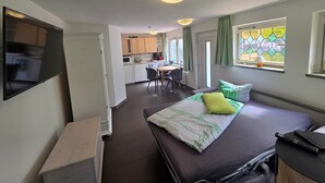 Une pièce de taille modeste comprenant un lit, un bureau et une kitchenette.