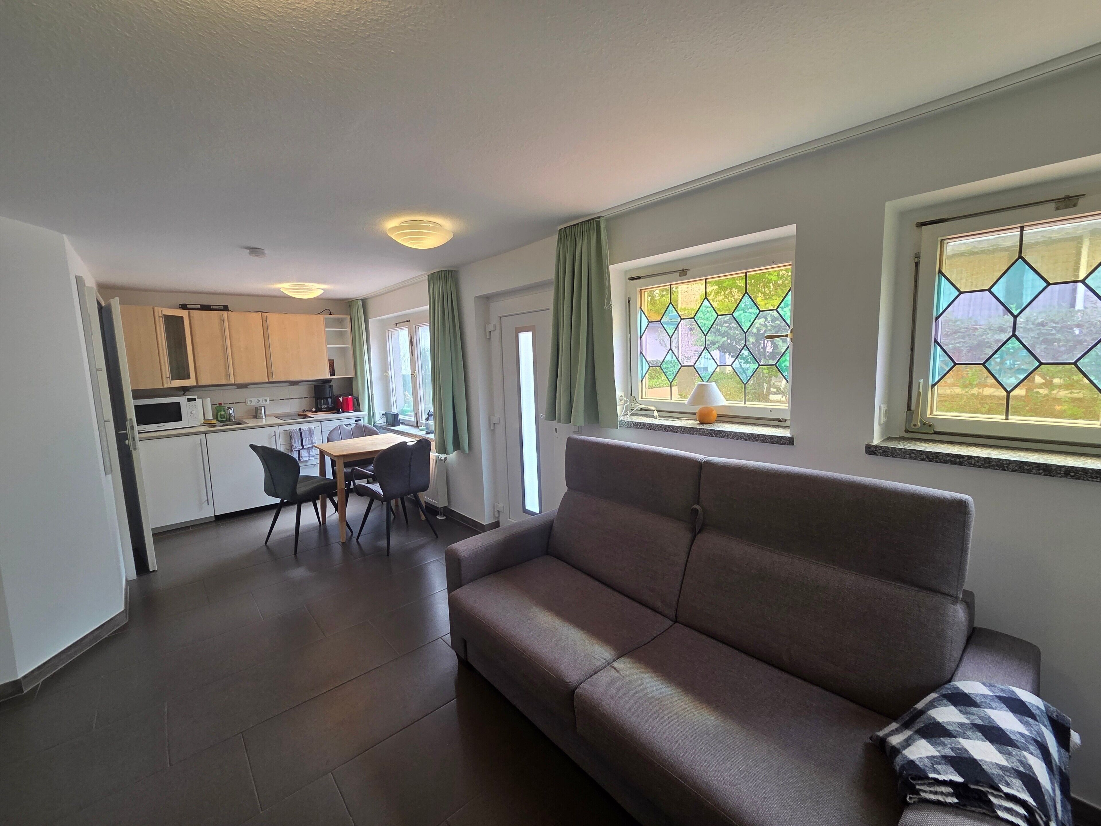A modern living room with a sofa and a dining area with a table and chairs.
