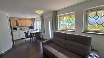 A modern living room with a sofa and a dining area with a table and chairs.