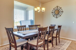 A dining area with a wooden table and chairs, a chandelier, and a decorative mirror on the wall. - Las Cruces Oasis: Patio, Hot Tub + Mtn Views (Las Cruces)