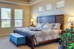 A bedroom with a large bed, a nightstand, a lamp, a bench, and a potted plant. - Las Cruces Oasis: Patio, Hot Tub + Mtn Views (Las Cruces)