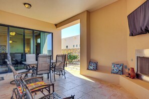 A covered patio area with a table and chairs, a view of the outside, and a wall with decorative items. - Las Cruces Oasis: Patio, Hot Tub + Mtn Views (Las Cruces)