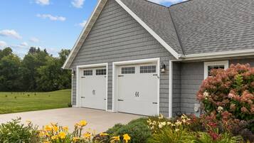 A two-car garage attached to a residential building with a sloped roof and a landscaped front yard.