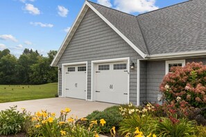 A two-car garage attached to a residential building with a sloped roof and a landscaped front yard.