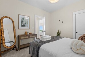 A hotel room with a bed, a dresser, a mirror, a door, and a framed picture on the wall.