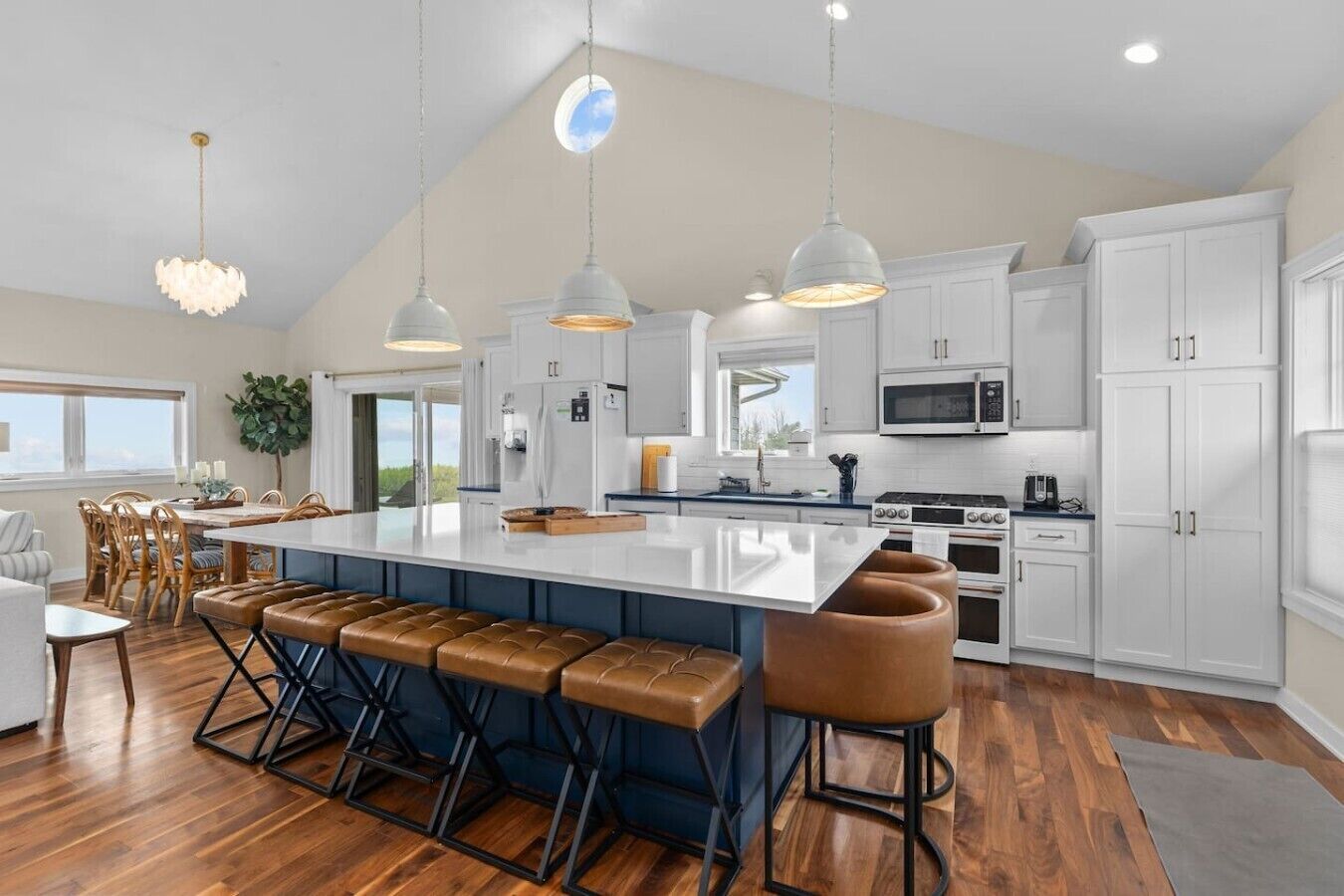 A modern kitchen with a large island, bar stools, and a dining area with a view.