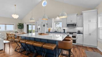 A modern kitchen with a large island, bar stools, and a dining area with a view.