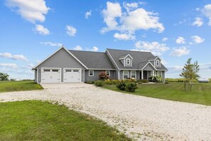 A two-story house with a garage, a driveway, and a well-maintained lawn.