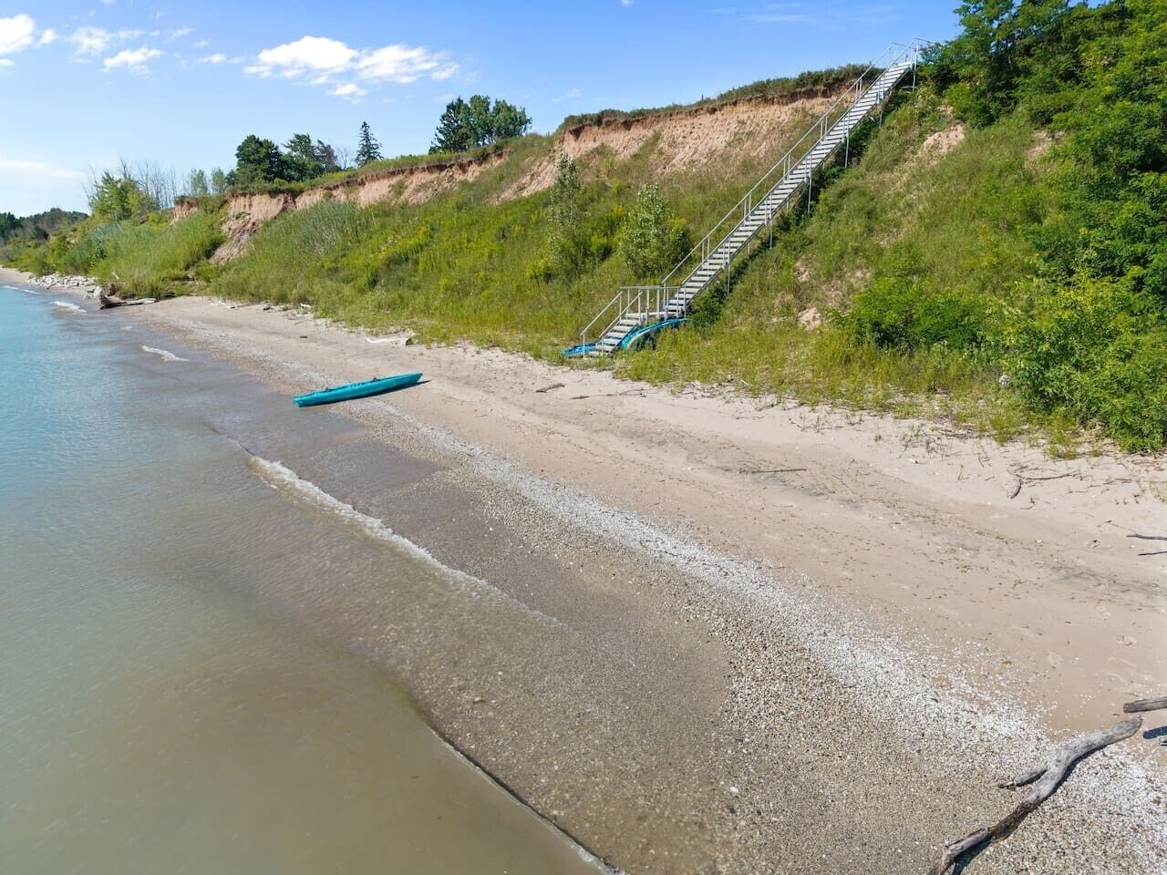 A beach with a staircase leading up a grassy slope.