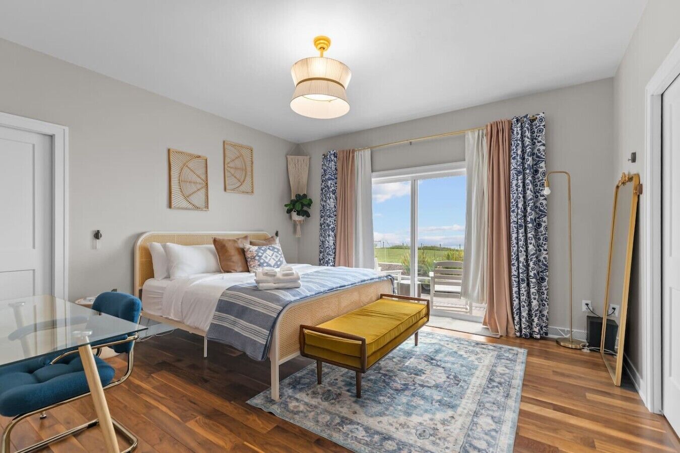 A bedroom with a bed, bedside table, and a view of the outdoors.