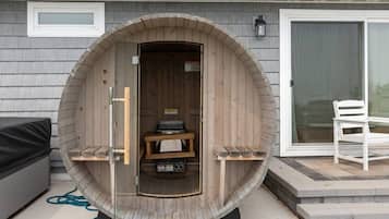 Una sauna con revestimiento de madera, un banco en el interior y una pequeña mesa con objetos encima.