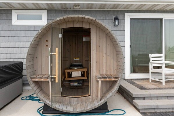 A sauna with a wooden exterior, a bench inside, and a small table with items on it.