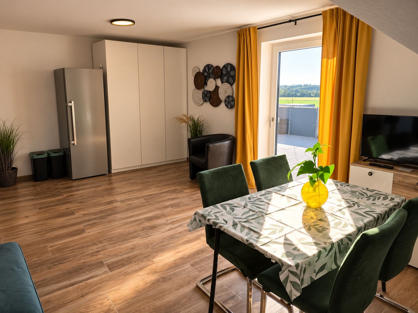 A modern kitchen with a built-in refrigerator, a dining area with a table and chairs, and a large window with curtains.
