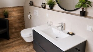 A modern bathroom with a white sink, black cabinet, and a round mirror. - Modern Apartment with a Balcony & Panoramic Views (Tirschenreuth)