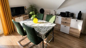 A modern dining area with a table, chairs, and a television. - Modern Apartment with a Balcony & Panoramic Views (Tirschenreuth)