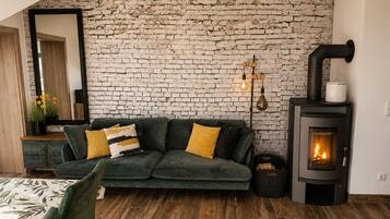 Una sala de estar acogedora con un sofá verde, una chimenea y una pared de ladrillo.