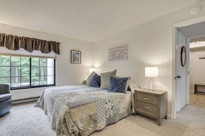 A bedroom with a bed, nightstands, a window with a view, a door, and a wall with a sign. - Lake Days, Pool Vibes! Family Retreat in Poconos (Lake Harmony)