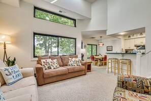 A spacious living area with a large window, a sofa, and a dining table. - Lake Days, Pool Vibes! Family Retreat in Poconos (Lake Harmony)