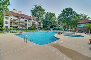 A swimming pool area with lounge chairs and umbrellas, surrounded by multi-story buildings with balconies. - Lake Days, Pool Vibes! Family Retreat in Poconos (Lake Harmony)