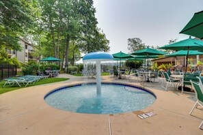 A pool area with a central water feature, surrounded by green umbrellas and lounge chairs. - Lake Days, Pool Vibes! Family Retreat in Poconos (Lake Harmony)