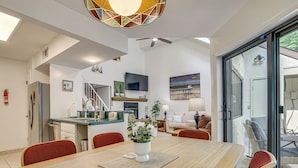 Una cucina moderna con una TV a schermo piatto, un'area pranzo con tavolo e sedie in legno e un soggiorno con divano e un quadro.