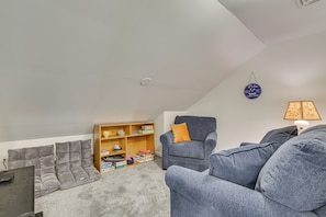 A cozy living room with a grey sofa, a wooden bookshelf, and a grey armchair. - Lake Days, Pool Vibes! Family Retreat in Poconos (Lake Harmony)