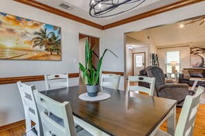 A dining area with a wooden table, white chairs, and a potted plant. - Mary Esther Family Home, 9 Mi to Navarre Beach! (Mary Esther)