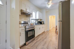 Una cocina con armarios blancos, electrodomésticos de acero inoxidable y piso de madera.